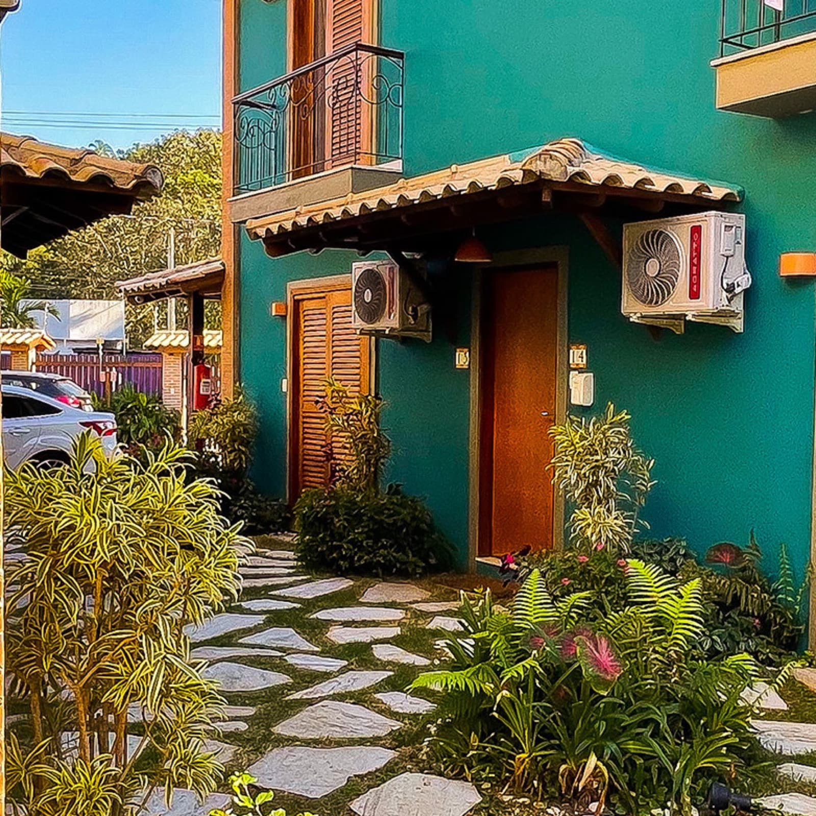 Chalé verde-azulado com portas de madeira e jardim tropical sob luz dourada