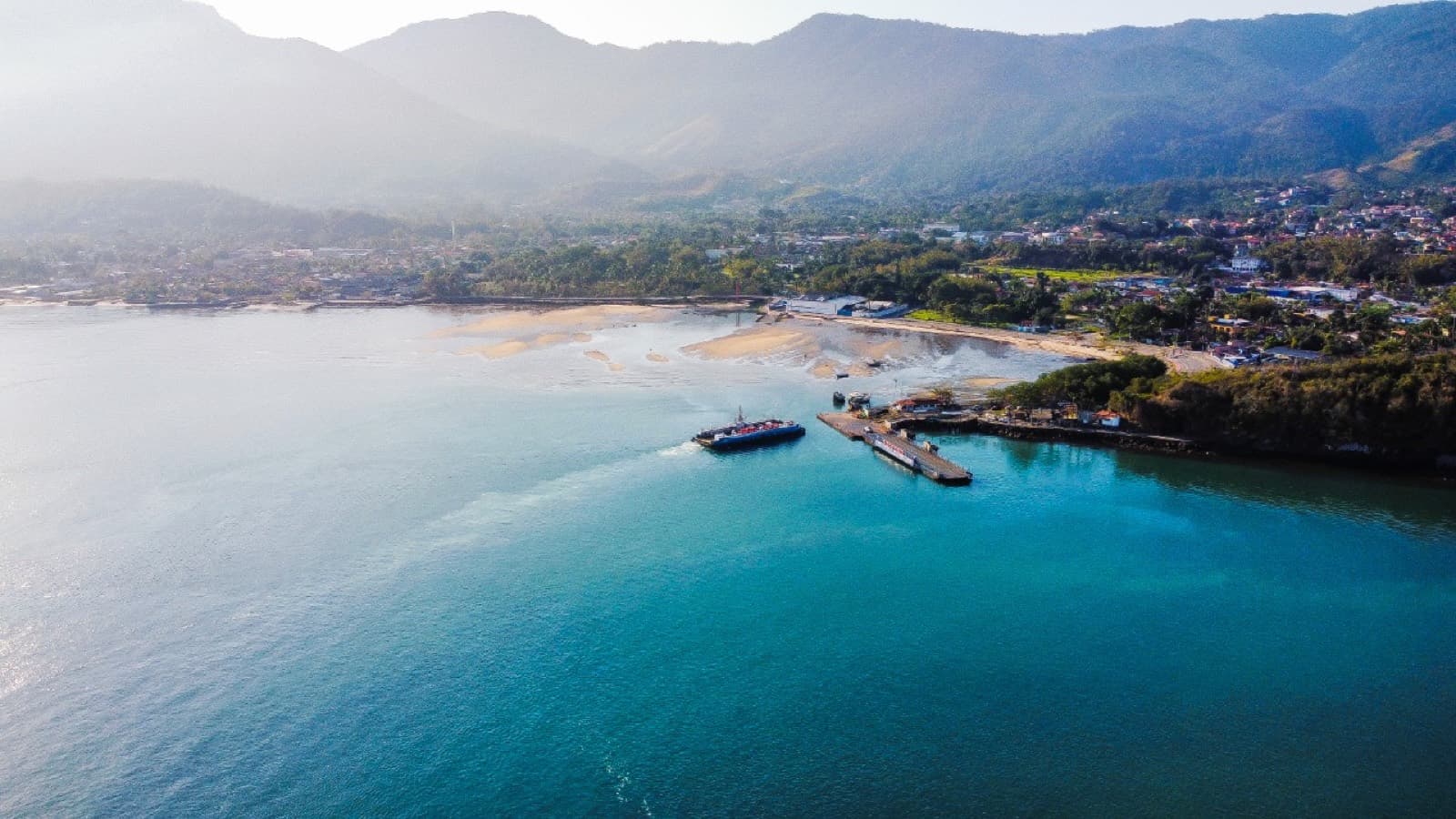 Vista aérea do litoral de Ilhabela com montanhas, praia e mar azul-turquesa